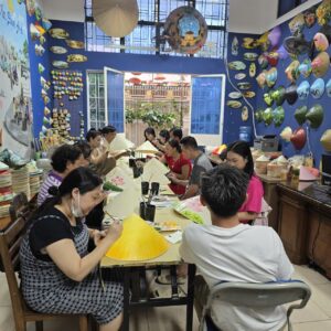 Guests painting conical hats at a Saigon workshop