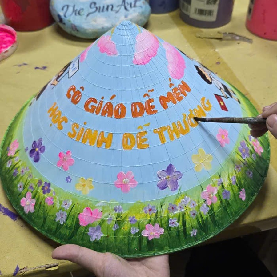 Hand-painted conical hat gift for a teacher with a message and spring flowers on a light blue background